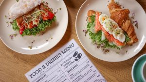 Top view of delicious salmon croissant and sandwich with fresh ingredients on wooden table.